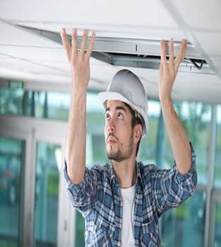Image: Worker installing ceiling tiles.