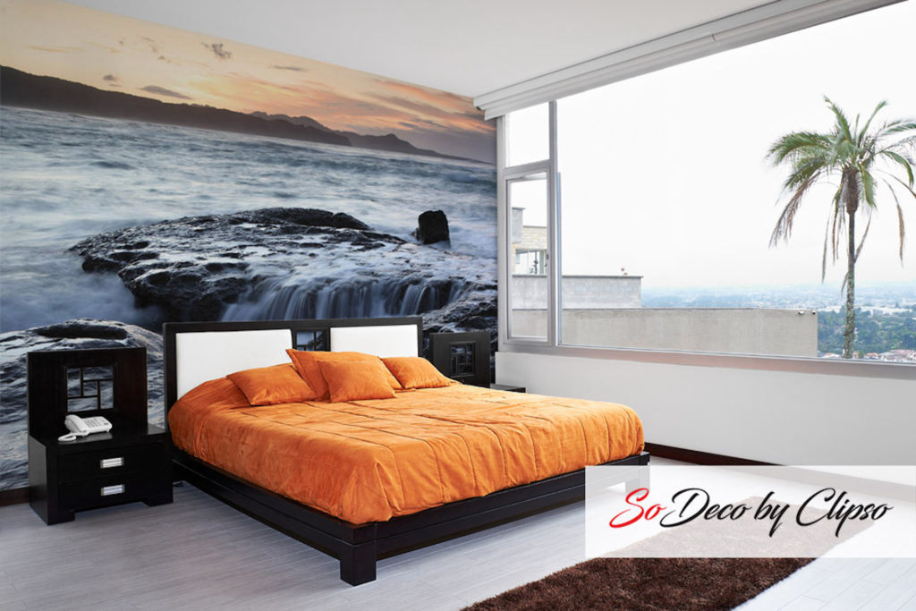 image of a bedroom with orange bedding and a CLIPSO stretch fabric wall of a rocky water fall